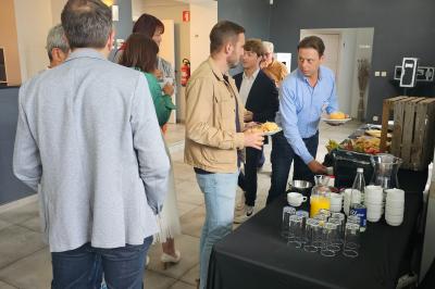 Des personnes se servent à un buffet dans un espace intérieur lumineux avec des boissons et des aliments disposés sur une…