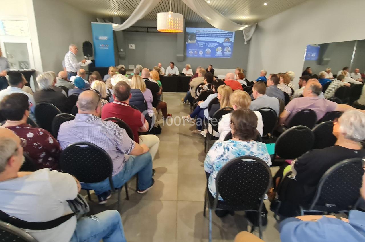 Salle comble avec des personnes assises écoutant un intervenant lors d'une réunion ou conférence.