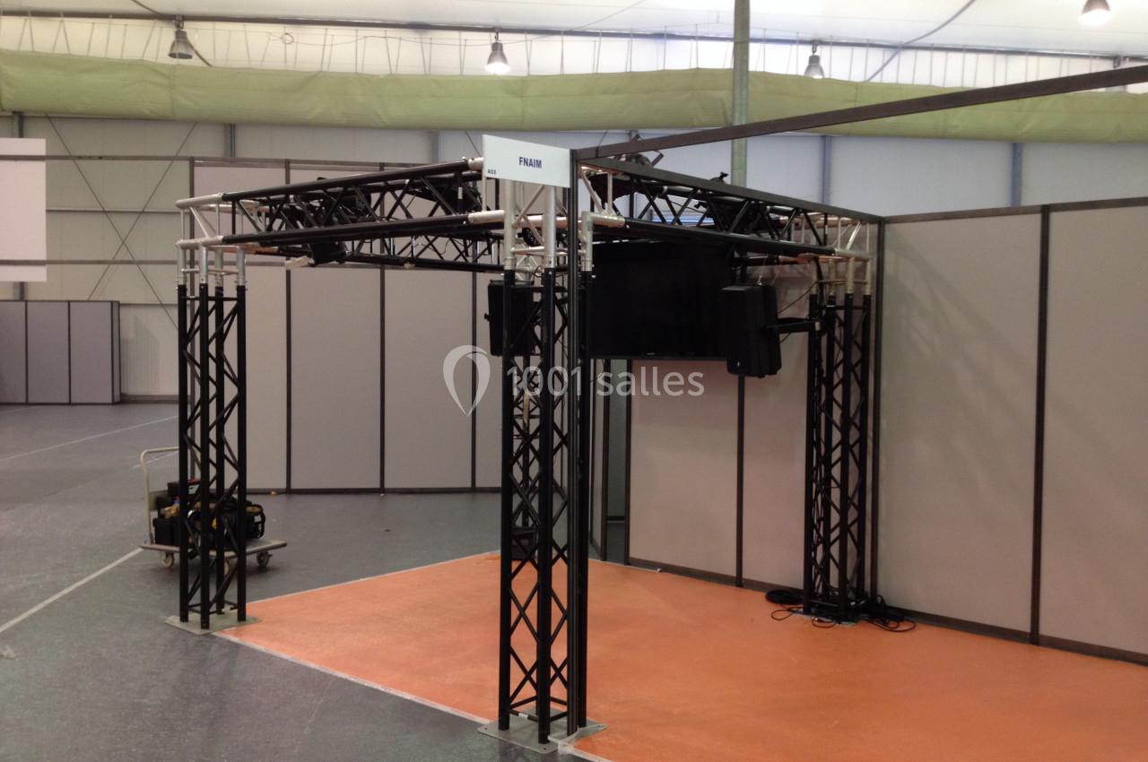 Structure métallique noire en forme de cadre, installée sur un sol orange dans un espace intérieur avec cloisons grises.