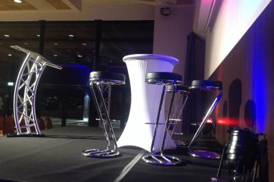 Salle de réception avec tables dressées et invités, éclairée par des lumières colorées et des motifs projetés au sol.