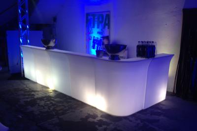 Salle de réception avec tables dressées et invités, éclairée par des lumières colorées et des motifs projetés au sol.