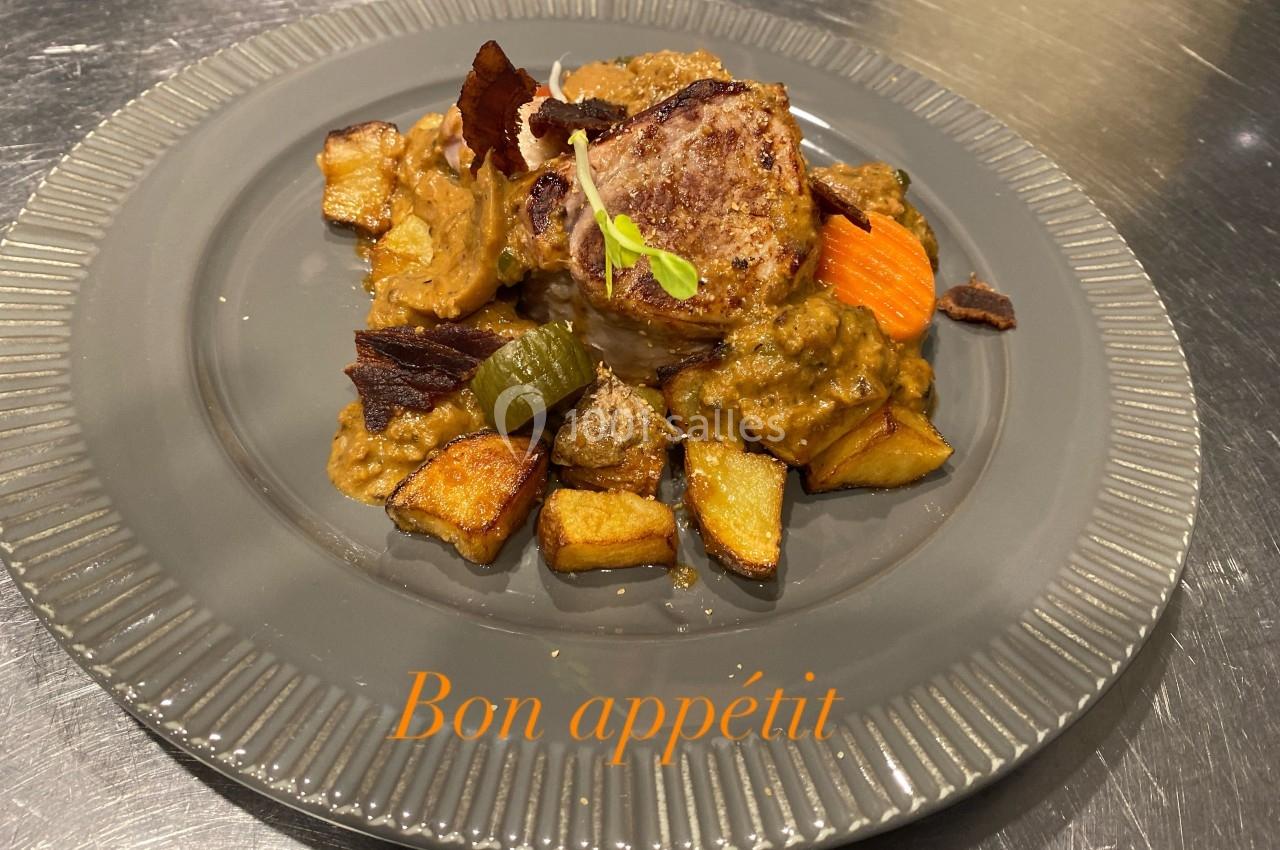 Assiette de viande grillée accompagnée de légumes rôtis et d'une sauce, servie sur une assiette grise.