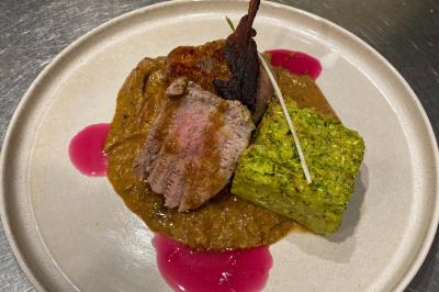 Dessert au chocolat avec framboises fraîches, éclats de biscuit et coulis, présenté sur une assiette en ardoise.