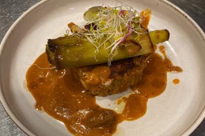 Dessert au chocolat avec framboises fraîches, éclats de biscuit et coulis, présenté sur une assiette en ardoise.