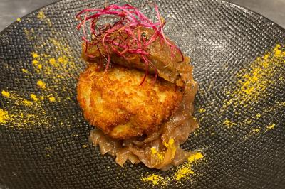 Dessert au chocolat avec framboises fraîches, éclats de biscuit et coulis, présenté sur une assiette en ardoise.