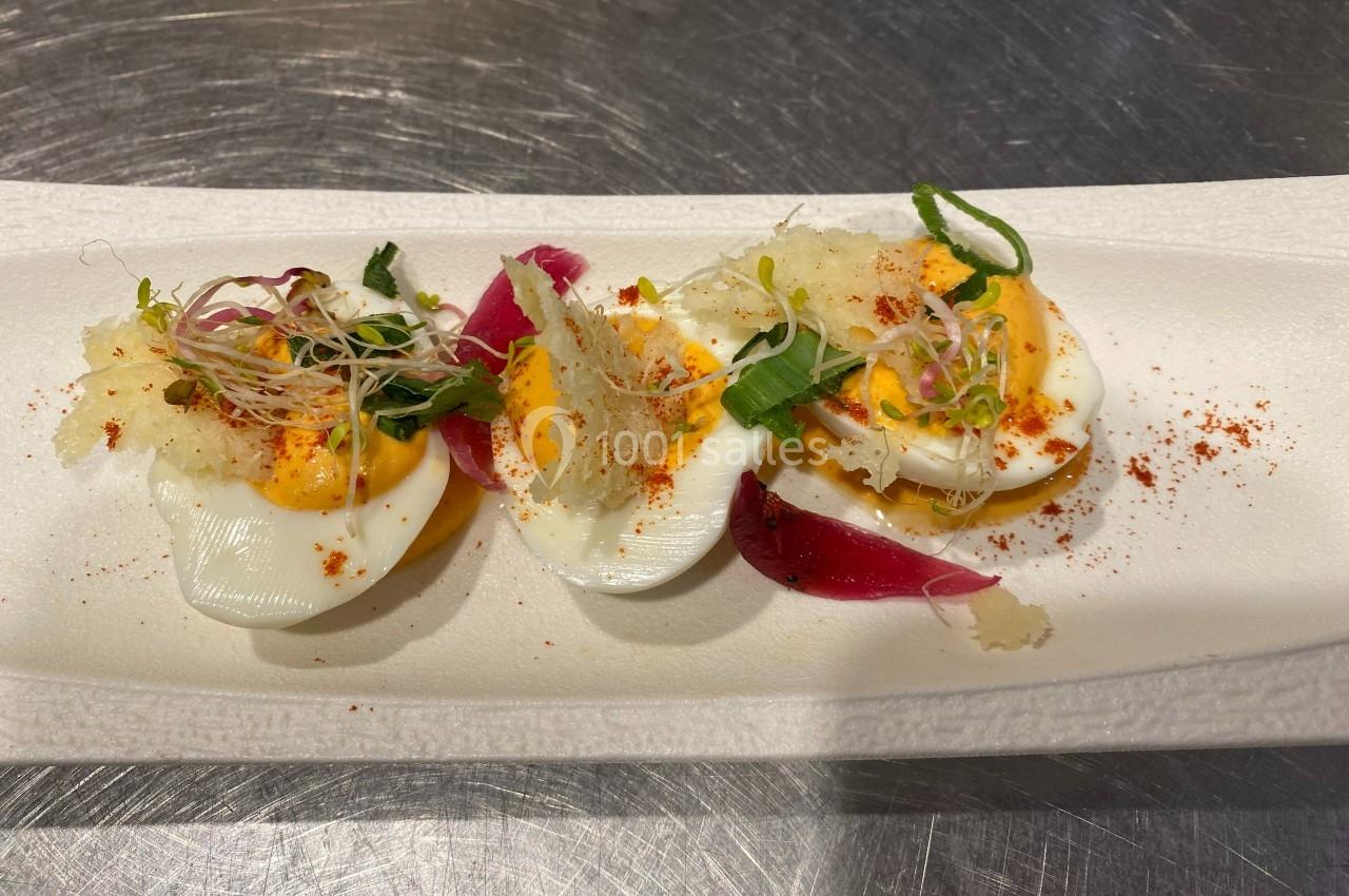 Trois moitiés d'œufs durs garnis de mayonnaise, herbes fraîches, germes et épices sur une assiette blanche.