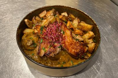 Dessert au chocolat avec framboises fraîches, éclats de biscuit et coulis, présenté sur une assiette en ardoise.