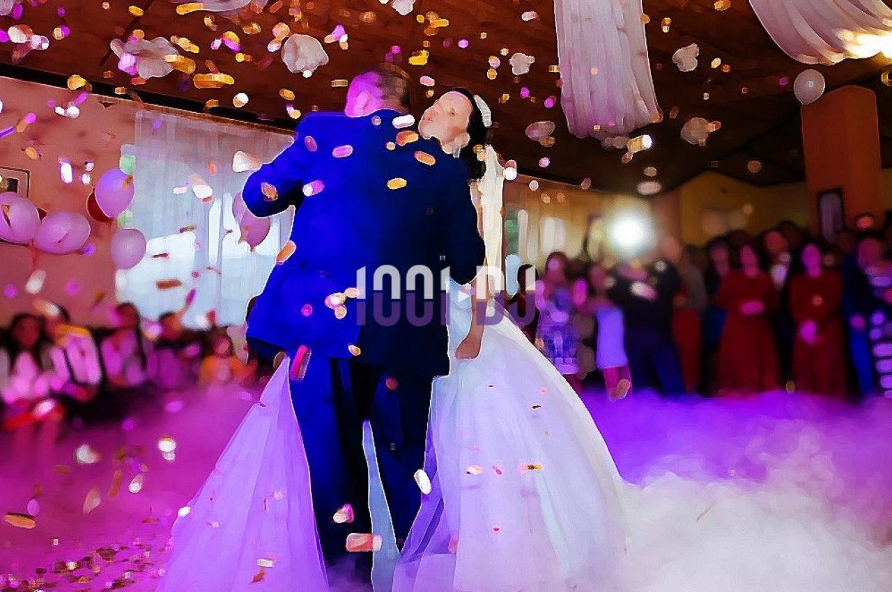Un couple danse au centre d'une salle décorée, entouré de confettis et d'invités en arrière-plan.