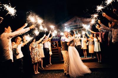 Tables hautes blanches dressées sur une pelouse avec des tonnelles blanches en arrière-plan.