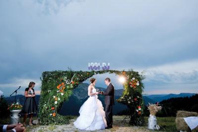 Tables hautes blanches dressées sur une pelouse avec des tonnelles blanches en arrière-plan.