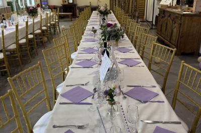 Salle de réception décorée avec de longues tables dressées, des chaises dorées et des nuages suspendus au plafond.