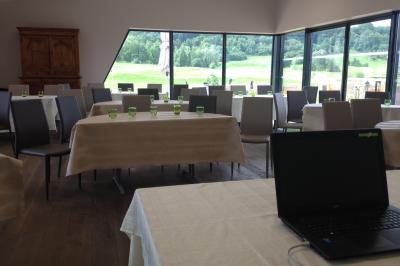 Des personnes rassemblées devant un bâtiment moderne avec des terrasses, des parasols et des voiturettes de golf.
