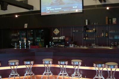 Des personnes rassemblées devant un bâtiment moderne avec des terrasses, des parasols et des voiturettes de golf.