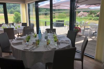 Des personnes rassemblées devant un bâtiment moderne avec des terrasses, des parasols et des voiturettes de golf.