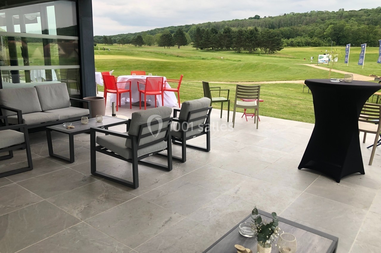 Terrasse aménagée avec mobilier de jardin, vue sur un terrain de golf et des collines verdoyantes en arrière-plan.