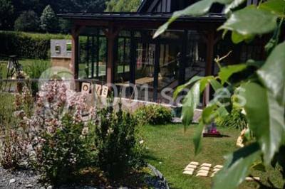 Deux tentes blanches installées sur une pelouse entourée de végétation et d'arbres sous un ciel bleu.