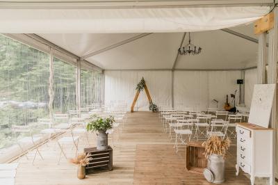Deux tentes blanches installées sur une pelouse entourée de végétation et d'arbres sous un ciel bleu.