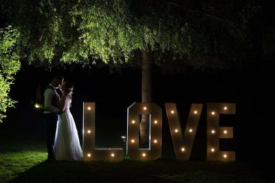 Deux tentes blanches installées sur une pelouse entourée de végétation et d'arbres sous un ciel bleu.