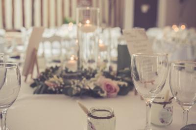 Deux tentes blanches installées sur une pelouse entourée de végétation et d'arbres sous un ciel bleu.