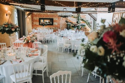 Deux tentes blanches installées sur une pelouse entourée de végétation et d'arbres sous un ciel bleu.
