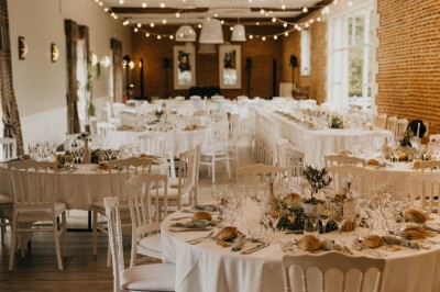 Deux tentes blanches installées sur une pelouse entourée de végétation et d'arbres sous un ciel bleu.