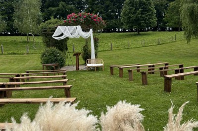 Deux tentes blanches installées sur une pelouse entourée de végétation et d'arbres sous un ciel bleu.
