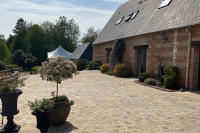 Deux tentes blanches installées sur une pelouse entourée de végétation et d'arbres sous un ciel bleu.