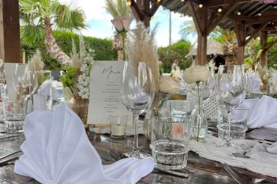 Salle de réception élégante avec tables rondes décorées de fleurs blanches et serviettes pliées, ambiance lumineuse.