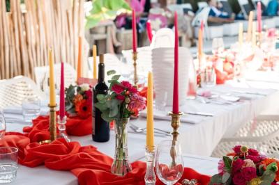 Salle de réception élégante avec tables rondes décorées de fleurs blanches et serviettes pliées, ambiance lumineuse.