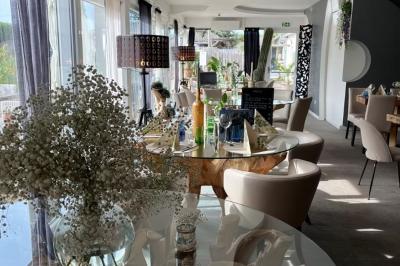 Salle de réception élégante avec tables rondes décorées de fleurs blanches et serviettes pliées, ambiance lumineuse.