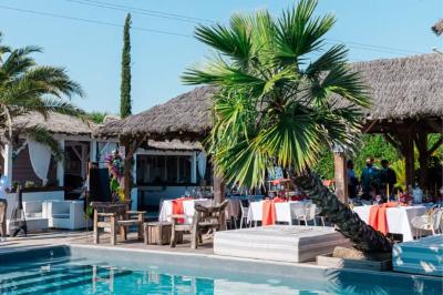 Salle de réception élégante avec tables rondes décorées de fleurs blanches et serviettes pliées, ambiance lumineuse.