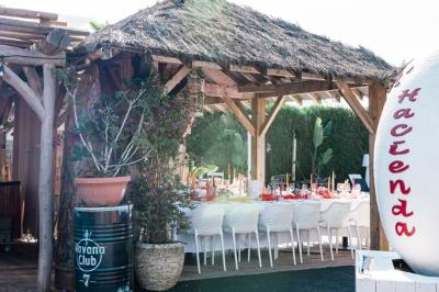 Salle de réception élégante avec tables rondes décorées de fleurs blanches et serviettes pliées, ambiance lumineuse.