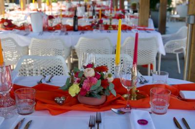 Salle de réception élégante avec tables rondes décorées de fleurs blanches et serviettes pliées, ambiance lumineuse.