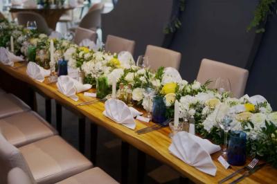Salle de réception élégante avec tables rondes décorées de fleurs blanches et serviettes pliées, ambiance lumineuse.