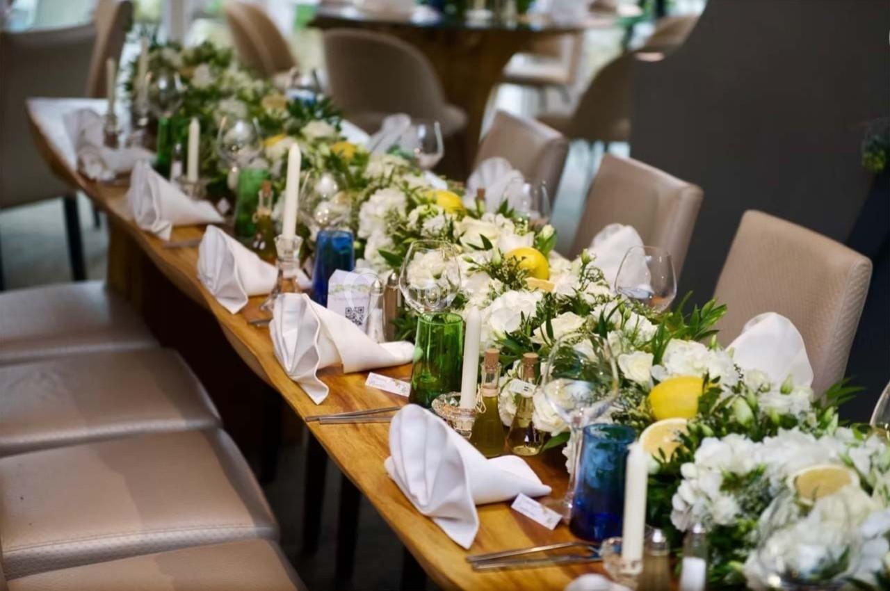 Table élégamment dressée avec nappes blanches, bougies, fleurs blanches et citrons en décoration.