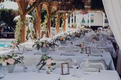 Salle de réception élégante avec tables rondes décorées de fleurs blanches et serviettes pliées, ambiance lumineuse.