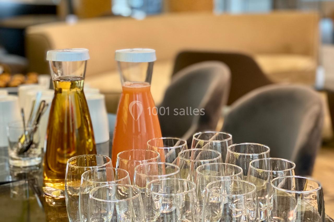 Carafes de jus et d'eau avec des verres vides disposés sur une table dans un espace intérieur lumineux.