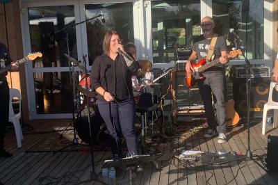 Tables rondes empilées verticalement et chaises empilées dans un couloir étroit avec un sol en carrelage gris.