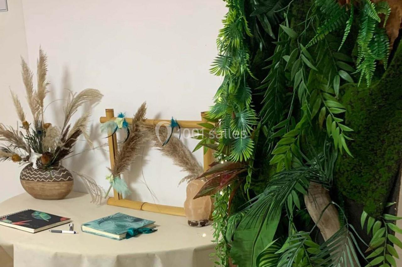 Décoration intérieure avec plantes artificielles, vase de pampas et livres posés sur une table beige.