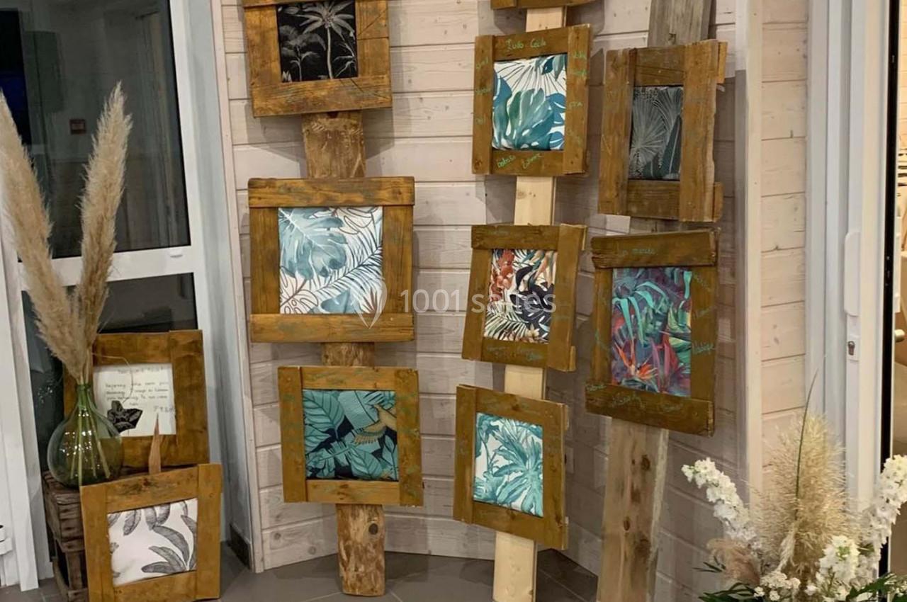 Cadres en bois contenant des illustrations végétales, disposés contre un mur en bois clair dans un espace intérieur.