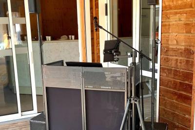 Tables rondes empilées verticalement et chaises empilées dans un couloir étroit avec un sol en carrelage gris.