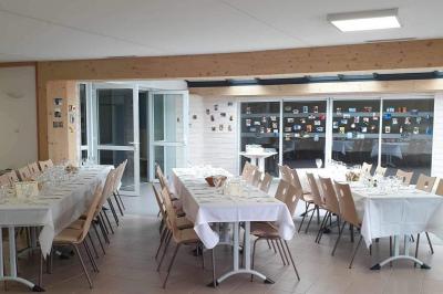 Tables rondes empilées verticalement et chaises empilées dans un couloir étroit avec un sol en carrelage gris.
