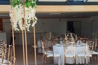 Tables rondes empilées verticalement et chaises empilées dans un couloir étroit avec un sol en carrelage gris.