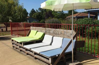 Tables rondes empilées verticalement et chaises empilées dans un couloir étroit avec un sol en carrelage gris.