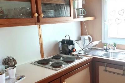 Tables rondes empilées verticalement et chaises empilées dans un couloir étroit avec un sol en carrelage gris.