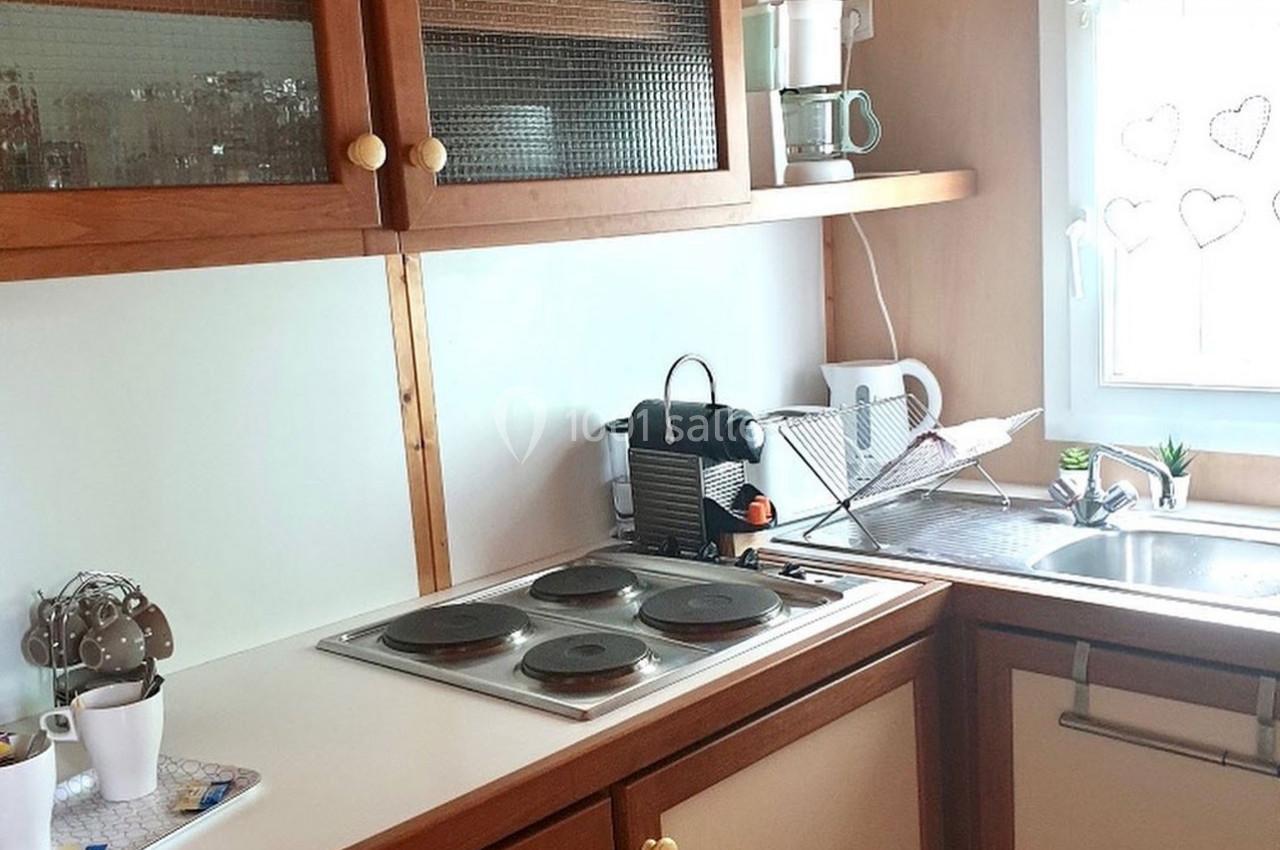 Cuisine lumineuse avec plaques de cuisson, évier, machine à café et rangements en bois clair.