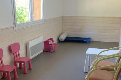 Tables rondes empilées verticalement et chaises empilées dans un couloir étroit avec un sol en carrelage gris.