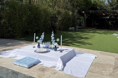 Table dressée avec vaisselle et fleurs bleues près d'une piscine entourée de dalles claires et de végétation.