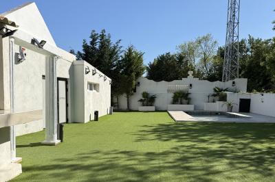 Table dressée avec vaisselle et fleurs bleues près d'une piscine entourée de dalles claires et de végétation.