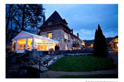 Salle décorée avec des ballons blancs et dorés, rangées de chaises rouges alignées sur un tapis rouge.